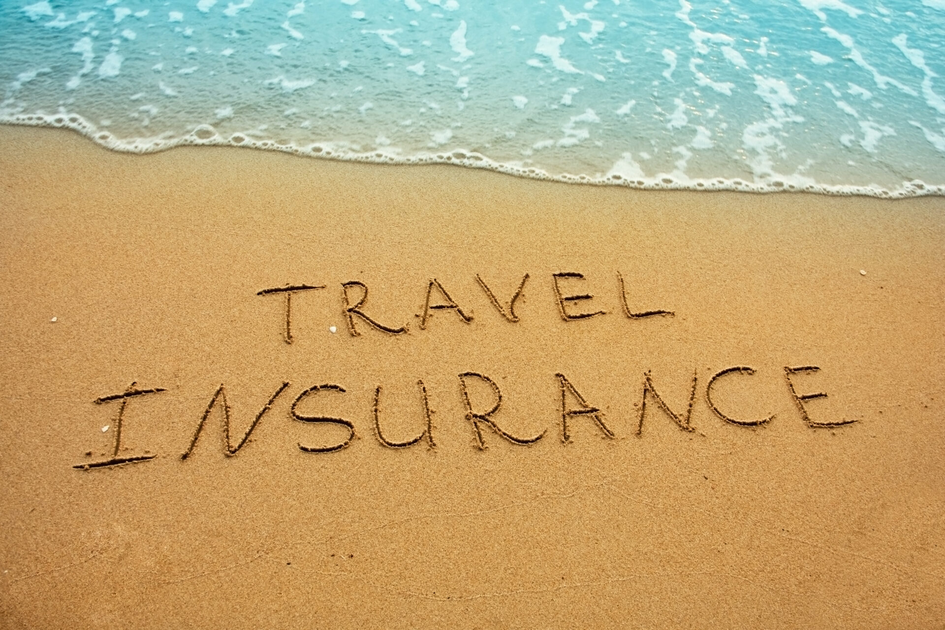 A beach with the words travel insurance written in it.