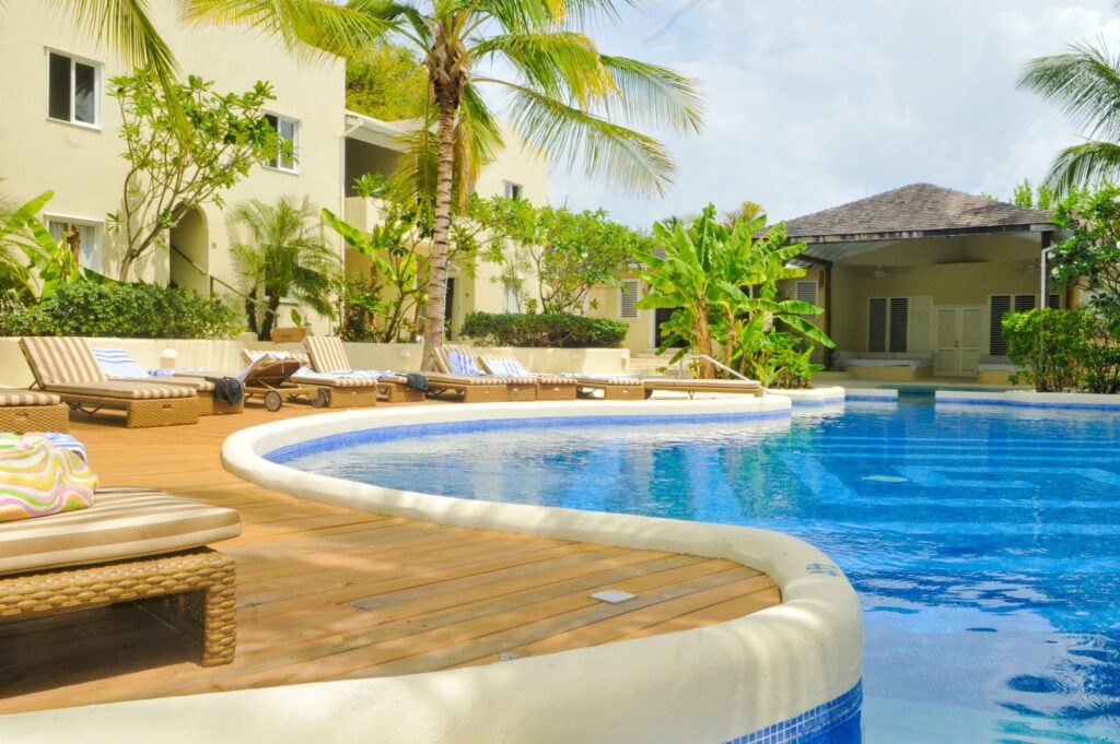 A pool with a wooden deck and palm trees.