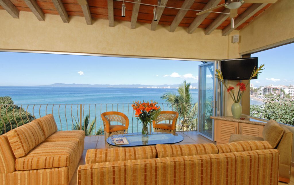 A living room with a large window overlooking the ocean.