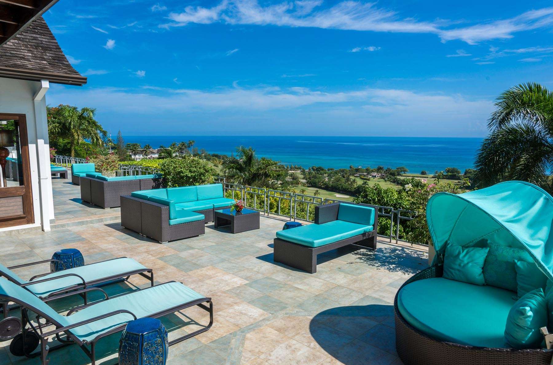 A patio with blue furniture and chairs overlooking the ocean.