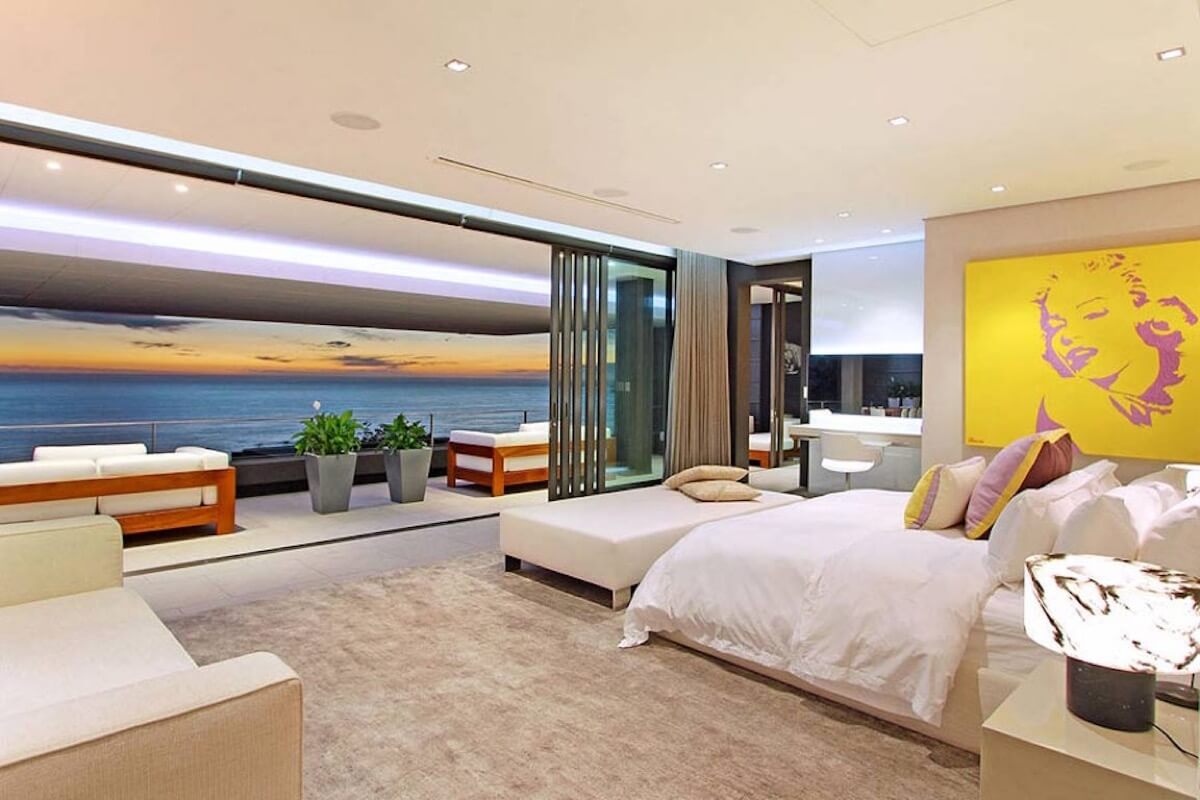 A bedroom with a large window and a view of the ocean.