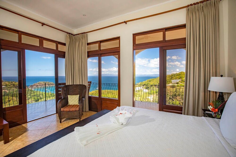 A bedroom with a view of the ocean and a chair.