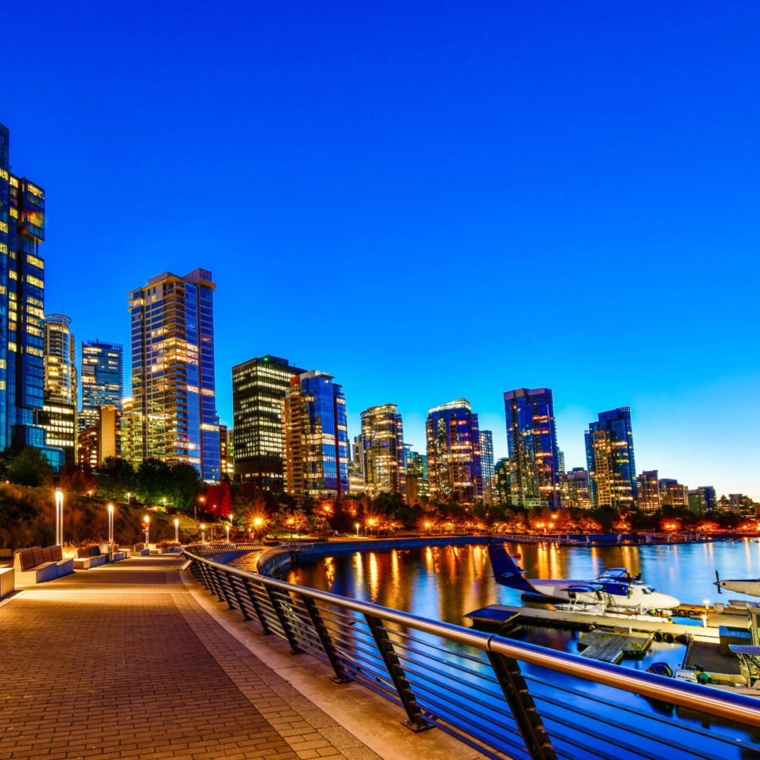 A city skyline with buildings and water at night.