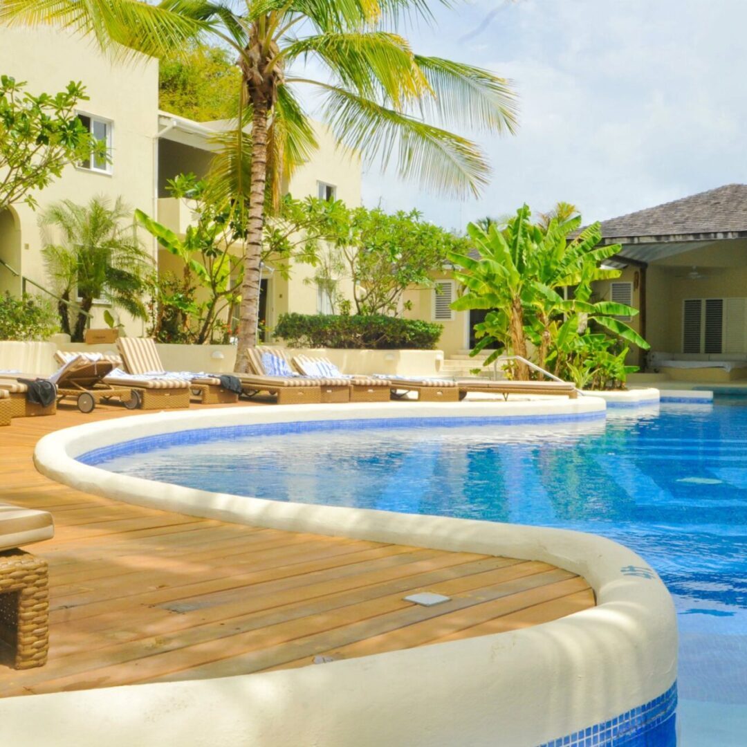 A pool with a wooden deck and palm trees.