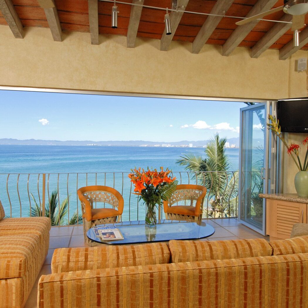 A living room with a large window overlooking the ocean.